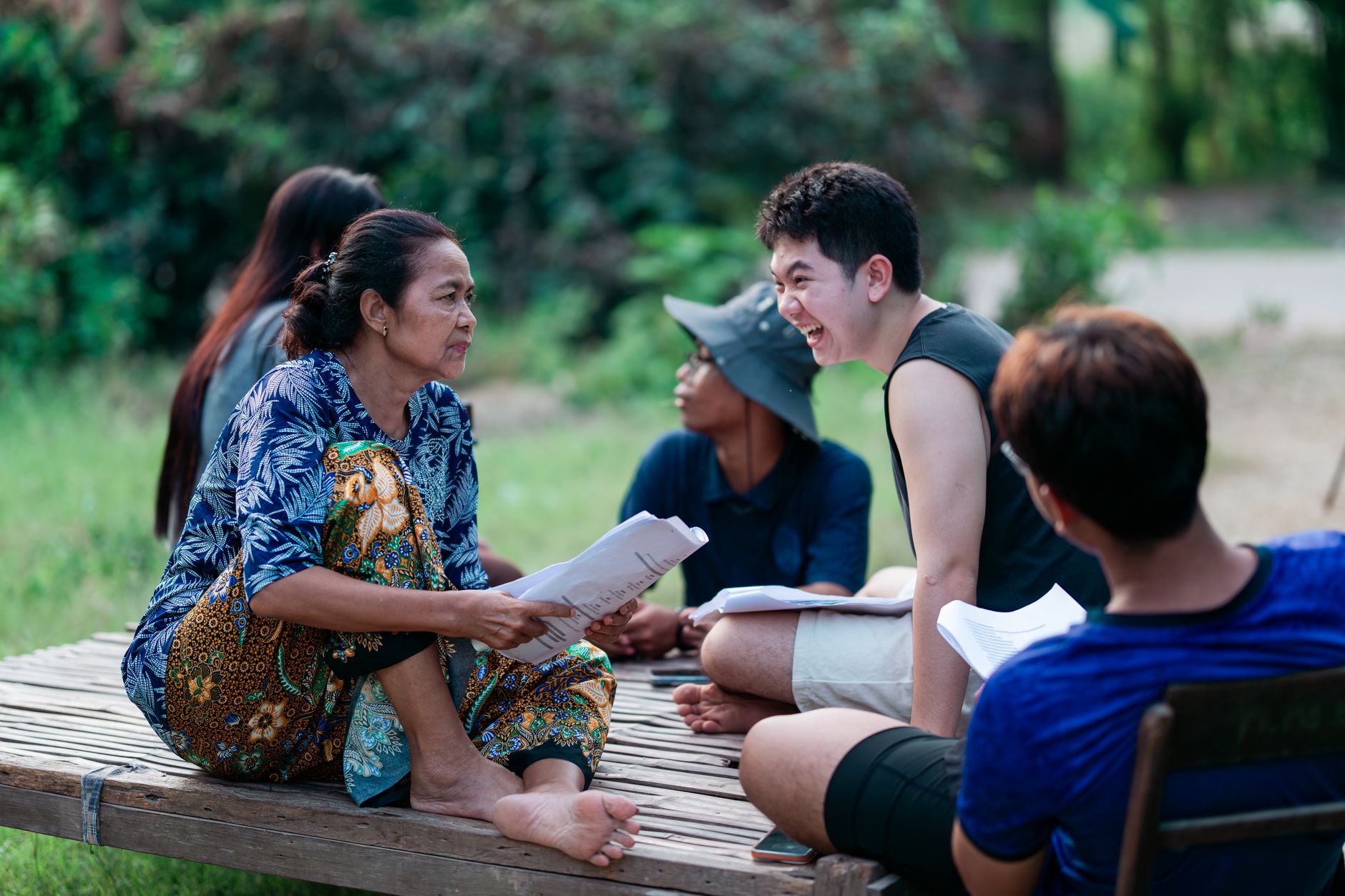 A diverse group enjoying a lively conversation outdoors on a sunny day.